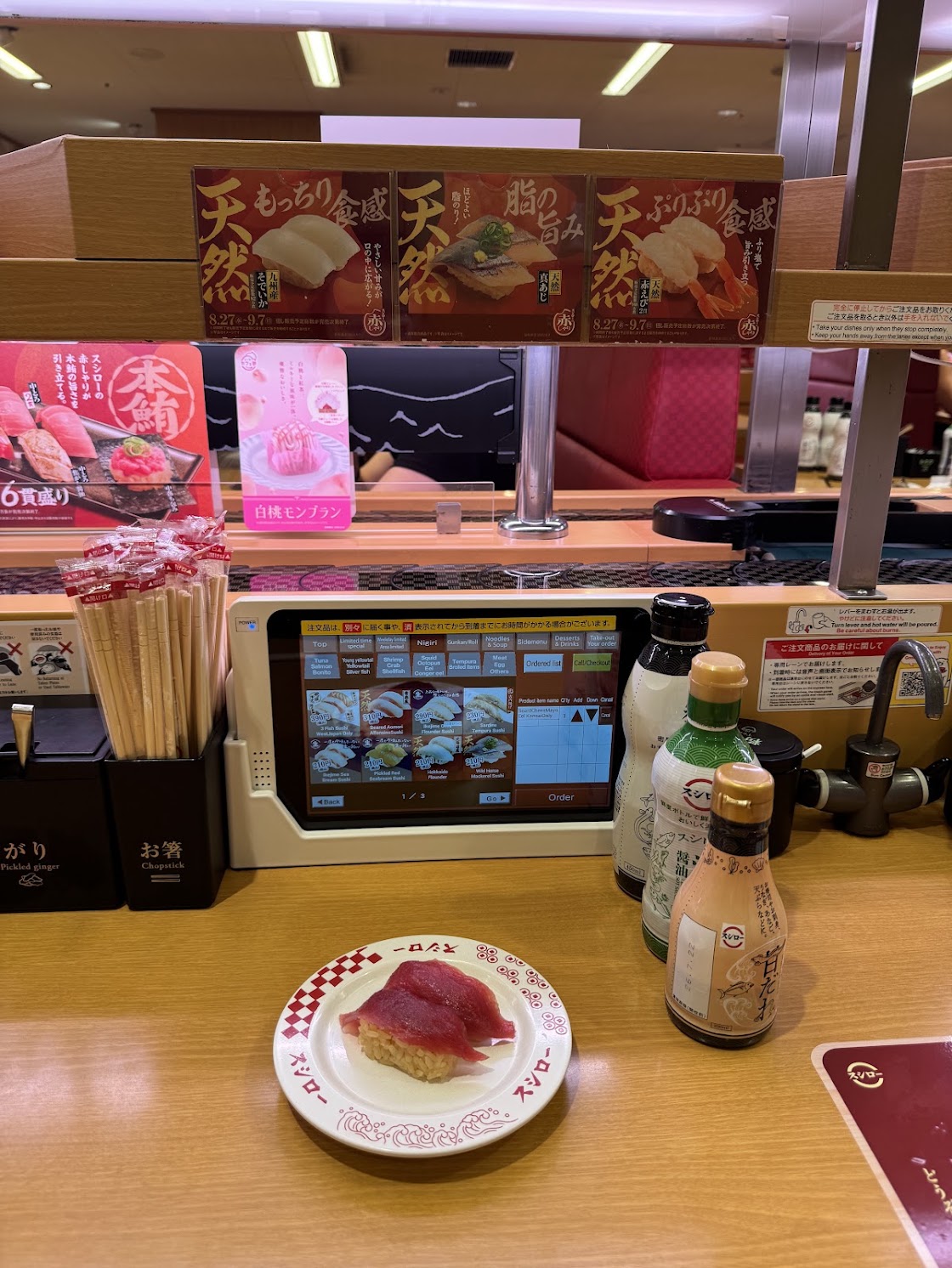 A plate of tuna nigiri at a conveyor-belt Sushiro in Kyoto, with the ordering tablet and condiments on the counter.